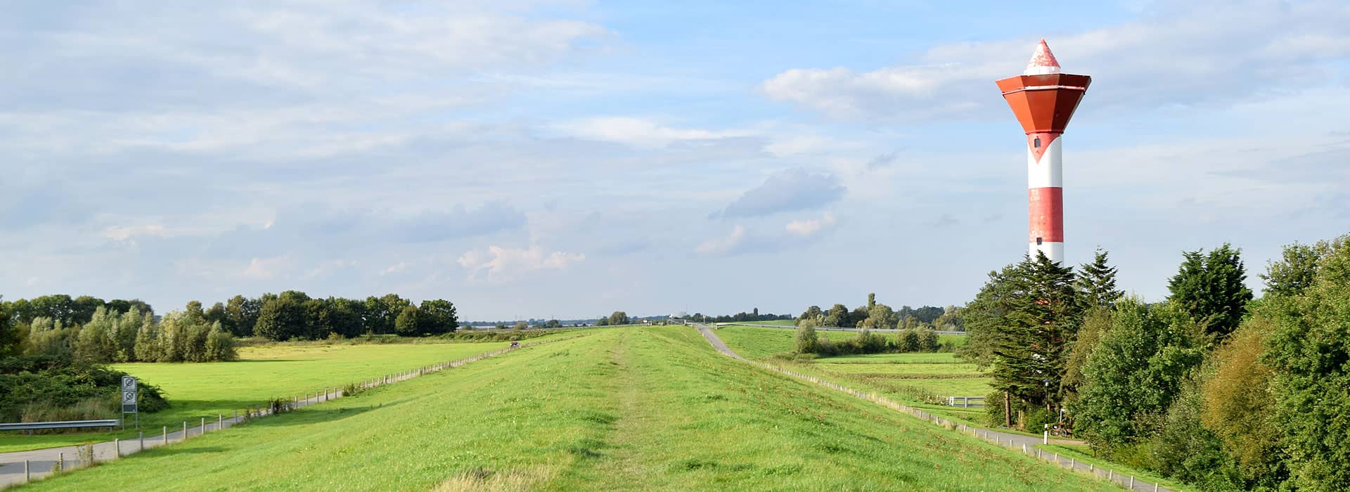 Ausblick vom Deich in die Landschaft mit einem Leuchtturm
